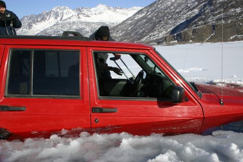 2003 Jeep TJ - A red Jeep Cherokee is stuck in ice with mountains in the background.