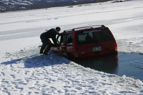 2003 Jeep TJ - Jeep Cherokee stuck in ice and water, person attempting to push it out.
