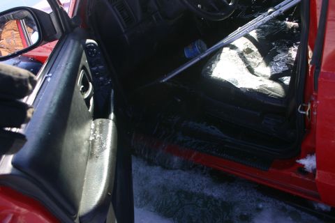 2003 Jeep TJ - The interior of a red vehicle shows a broken window and snow on the ground.