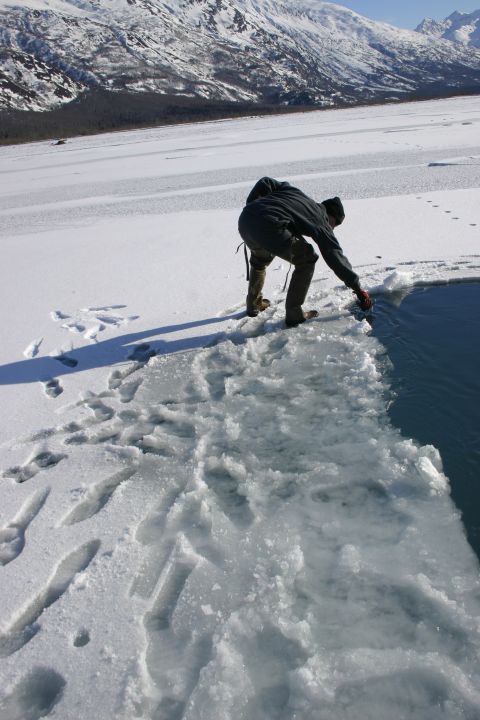 2003 Jeep TJ - Person interacting with water at the edge of an ice floe with snowy mountains behind.