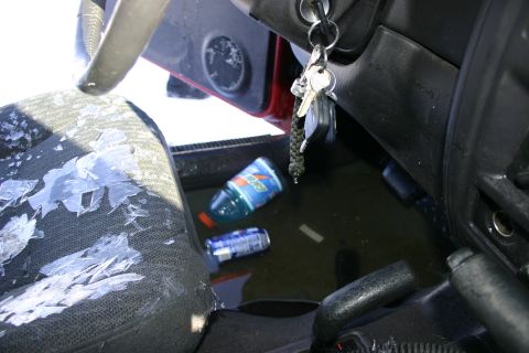 2003 Jeep TJ - Keys in the ignition and drinks on the floor of a vehicle interior, suggesting a messy or abandoned state.