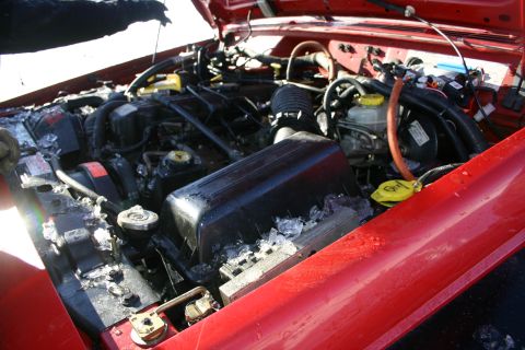 2003 Jeep TJ - Ice has accumulated in the engine bay of a red Jeep, suggesting it was exposed to freezing temperatures.