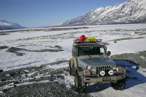2003 Jeep TJ - A silver 2003 Jeep TJ is parked in a snowy, mountainous terrain, equipped with a roof rack holding fuel cans.