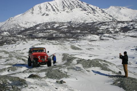 2003 Jeep TJ - Red Jeep TJ in a snowy mountain landscape with two people nearby.