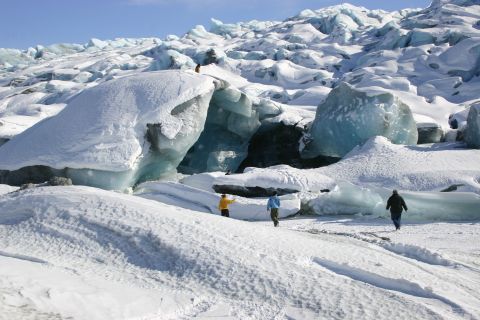 2003 Jeep TJ - People explore a vast, snow-covered glacier with striking blue ice formations under a clear sky.
