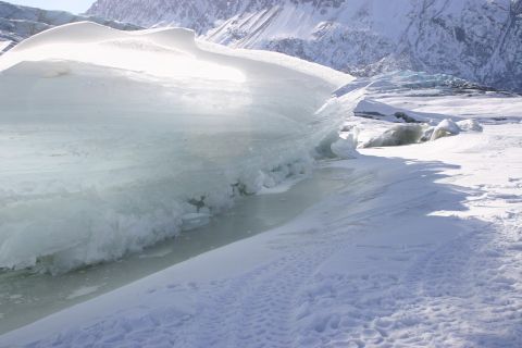2003 Jeep TJ - A large ice formation dominates the foreground of a snowy landscape, with mountains visible in the distance under a clear sky.