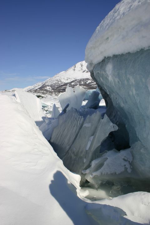 2003 Jeep TJ - A landscape scene of fractured ice and snow, with snow-capped mountains visible under a bright blue sky.