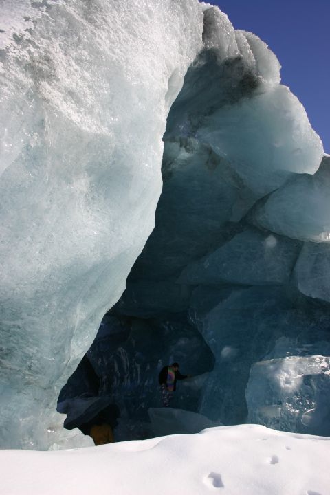 2003 Jeep TJ - A person explores the interior of a glacial ice cave on a clear day.