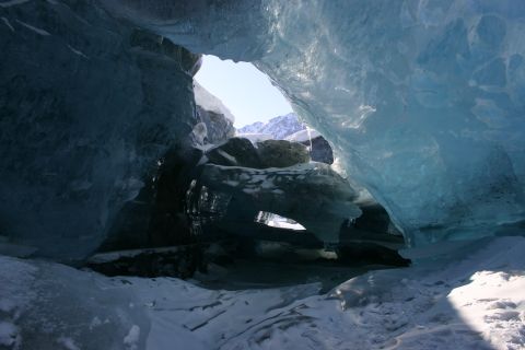 2003 Jeep TJ - View from within a glacial ice cave, with sunlight illuminating the entrance and distant mountains.