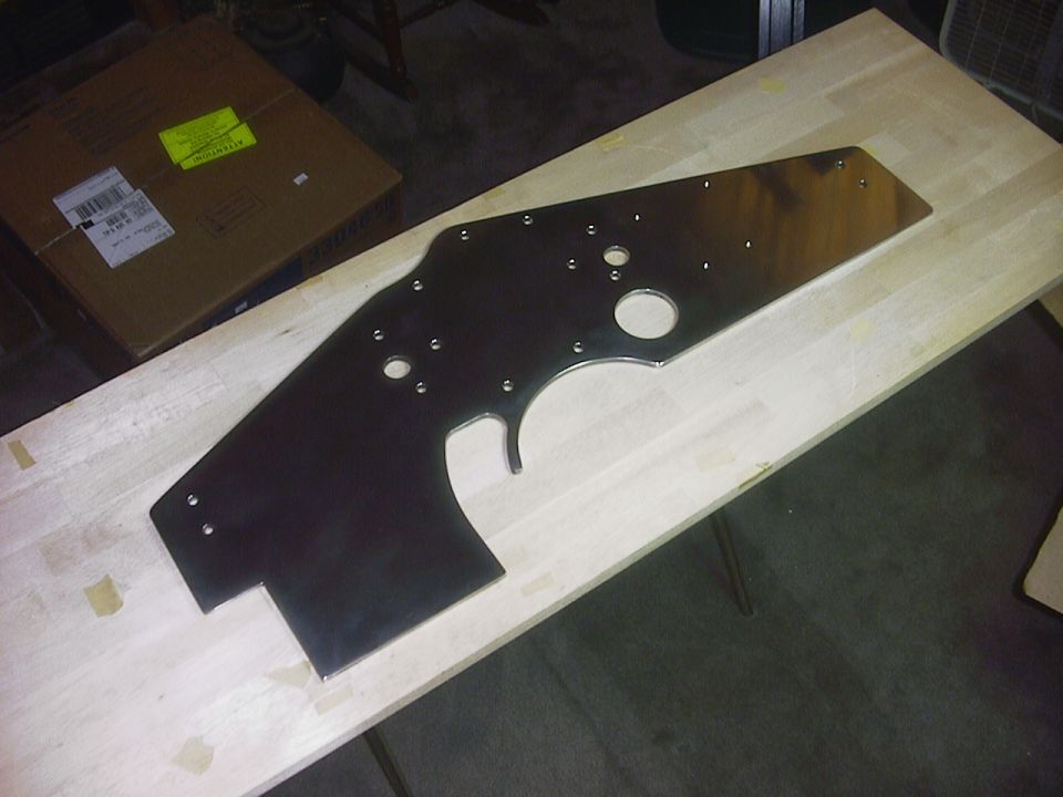 Polished metal engine part with multiple bolt holes on a wooden surface
