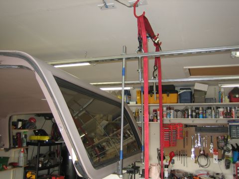 1996 Ford Bronco - A white removable fiberglass hardtop with tinted rear quarter and side glass hangs from a garage ceiling on red ratchet straps and a steel…