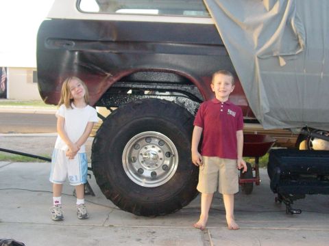 1979 Ford Bronco - Two children pose next to a 1979 Ford Bronco, highlighting its massive tires.