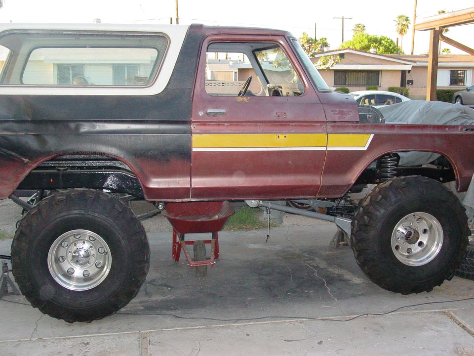Side view of a lifted Ford Bronco with large off-road tires, undergoing some work