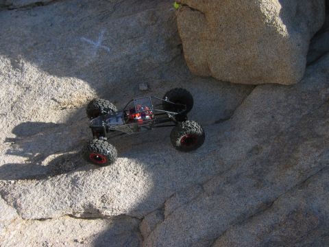 1985 Ford Bronco - A remote control rock crawler navigates a rocky terrain under bright sunlight.