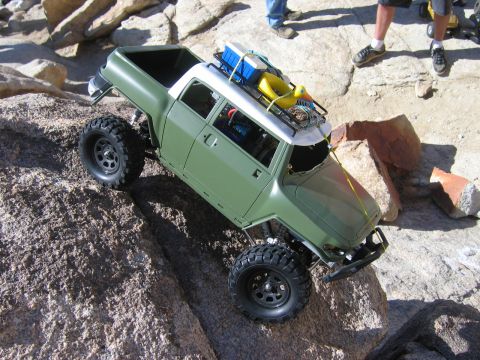 1985 Ford Bronco - A remote-controlled truck navigates a rocky terrain with a yellow duck on its roof rack.