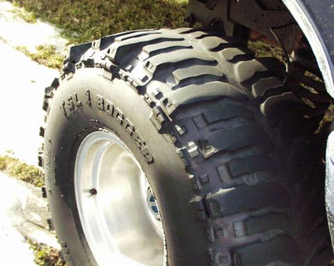 1989 Ford Bronco - Close-up of a TSL Bogger off-road tire mounted on a silver wheel, with visible suspension components.