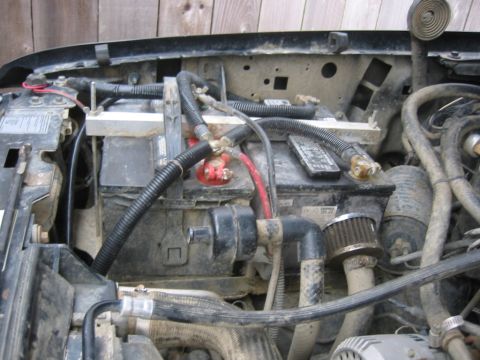 1995 Ford Bronco - Close-up view of the engine bay, focusing on the dual battery setup and associated wiring.