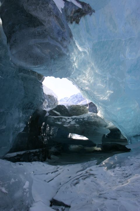 2003 Jeep TJ - View from within a glacial ice cave, with openings revealing a snow-covered mountainous landscape.