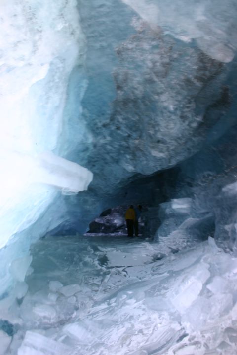 2003 Jeep TJ - Two individuals explore the depths of a blue ice cave, surrounded by frozen formations.