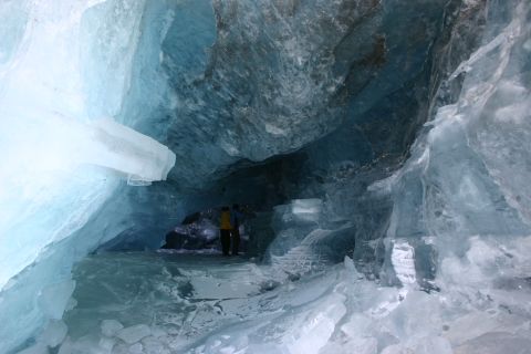 2003 Jeep TJ - Two people explore the interior of a blue ice cave, with formations of ice surrounding them.