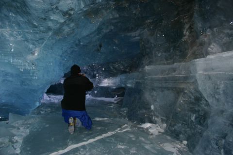 2003 Jeep TJ - A person explores the interior of a glacial ice cave, capturing the formations with a camera.