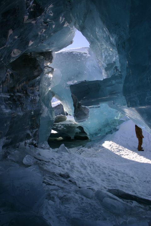 2003 Jeep TJ - A person stands in a sunlit ice cave, surrounded by blue ice formations and snow.
