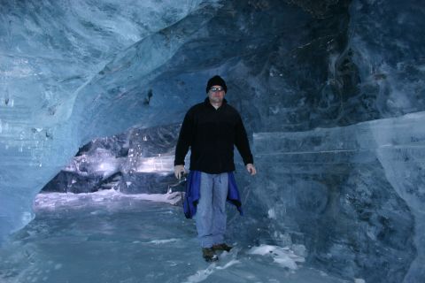 2003 Jeep TJ - A man stands inside a glacial ice cave, surrounded by blue ice formations.