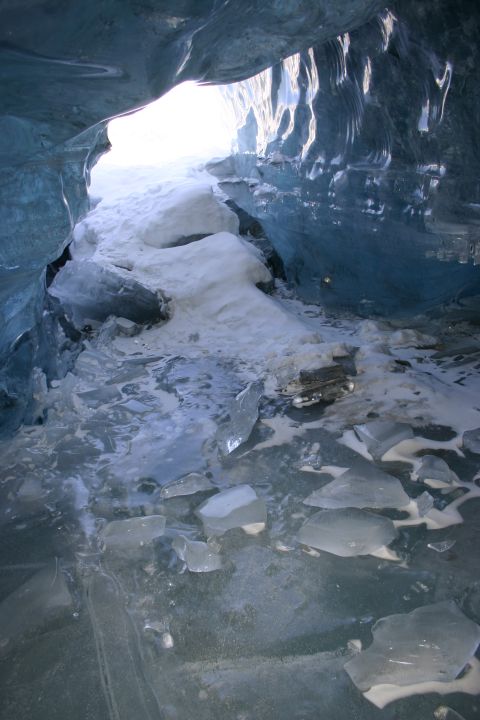 2003 Jeep TJ - View from inside a glacial ice cave, showing the textured blue ice walls and a path of broken ice leading to the exit.