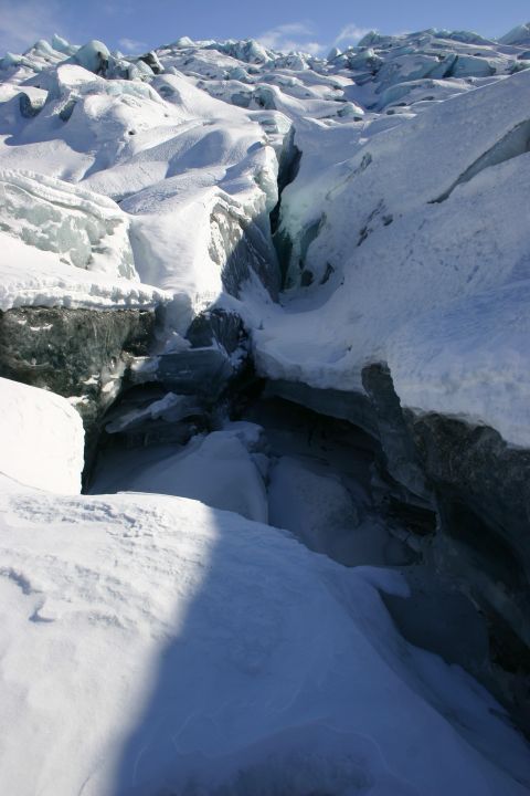 2003 Jeep TJ - A deep crevasse cuts through a snow-covered glacier, revealing layers of blue ice.