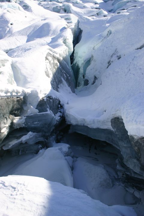 2003 Jeep TJ - A deep crevasse cuts through a snow-covered glacier, revealing layers of blue ice within its depths.