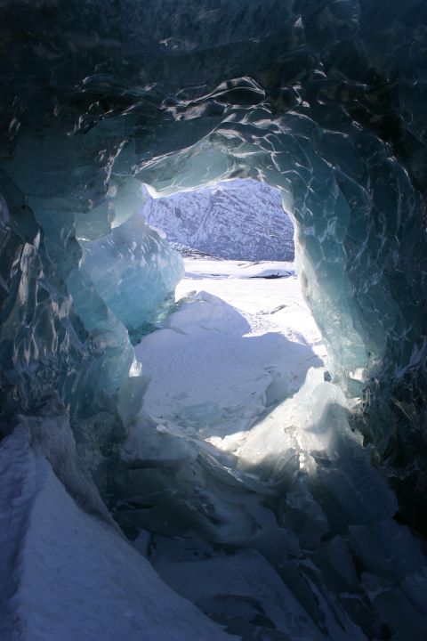 2003 Jeep TJ - Looking out from within a glacial ice cave at a snow-covered landscape and distant mountains.