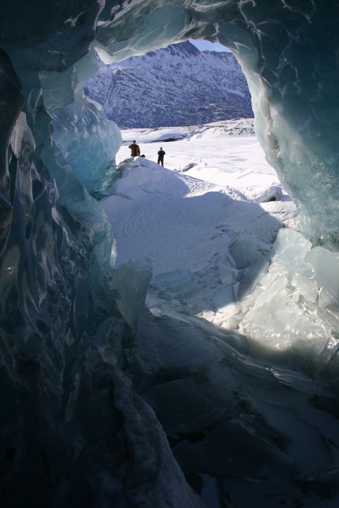 2003 Jeep TJ - View from inside an ice cave looking out at a snowy landscape with two figures in the distance.