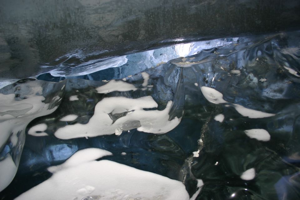 Ice cave interior with blue and white ice formations and patches of snow