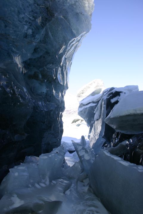 2003 Jeep TJ - View from inside a glacial ice cave, showing the textured blue ice walls and a bright opening to the sky.
