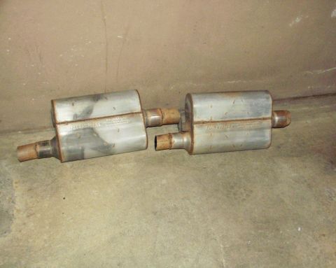 1989 Ford Bronco - Pair of Flowmaster mufflers, likely for a vehicle, shown on a concrete floor.