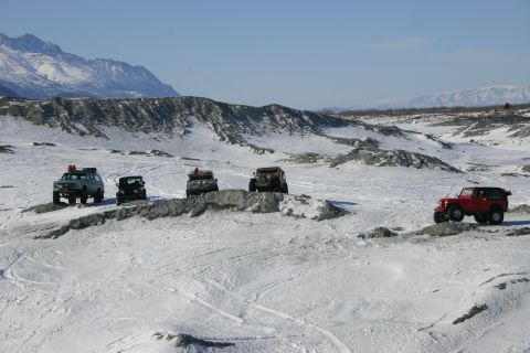 2003 Jeep TJ - Five Jeep Wranglers traverse a snow-covered, rocky landscape under a clear blue sky.