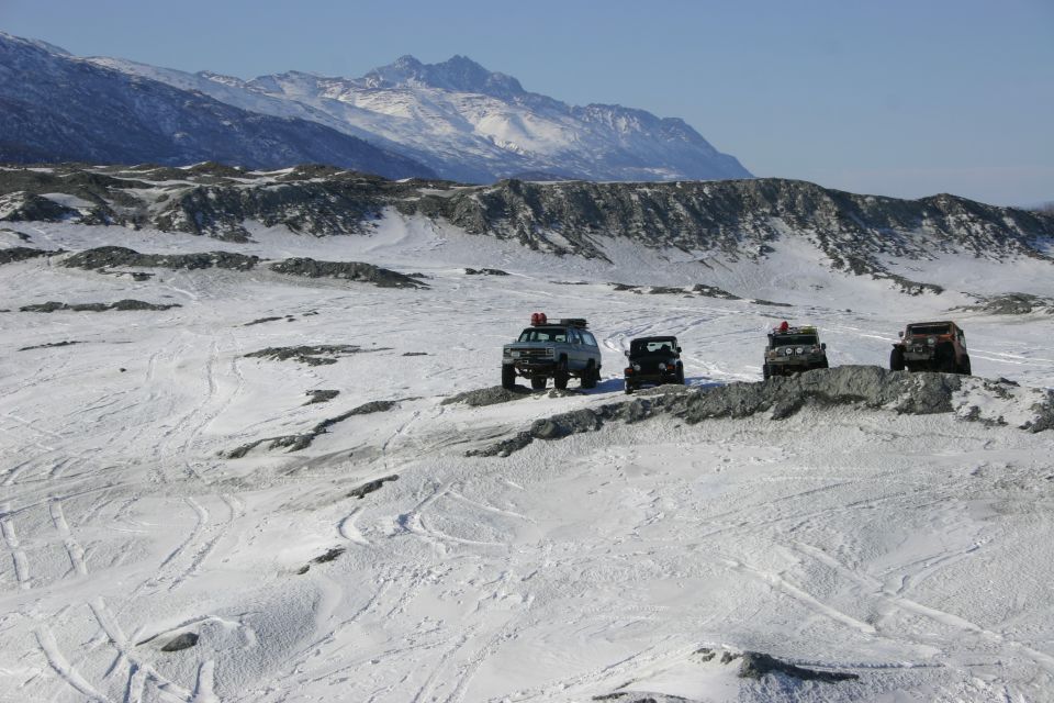 Four SUVs on snowy terrain with mountains