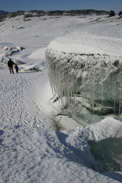 2003 Jeep TJ - A person and child walk through a snowy area with a large ice formation and icicles in the foreground.