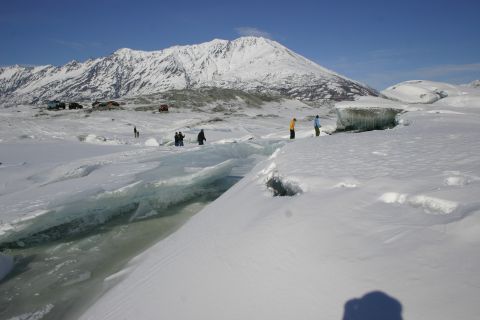 2003 Jeep TJ - People and vehicles explore a snowy landscape near a glacial crevasse with a mountain backdrop.