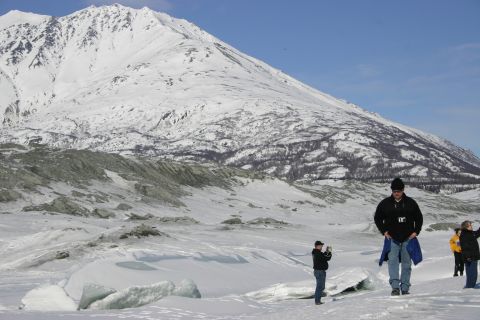 2003 Jeep TJ - A group of people stand in a snow-covered area with a large mountain dominating the background under a clear blue sky.