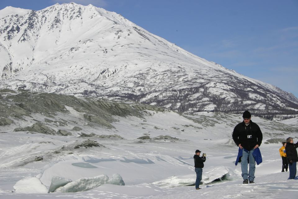 people in a snowy landscape with a large snow-covered mountain in the background