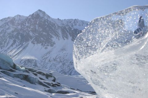 2003 Jeep TJ - A large ice formation is in the foreground, with a snow-covered mountain range and glacier in the background under a clear blue sky.