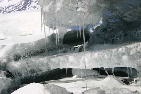 2003 Jeep TJ - Icicles hang from the ceiling of an ice cave opening, with snow-covered mountains in the background.