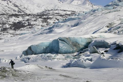 2003 Jeep TJ - A lone figure surveys the vast expanse of a snow-covered landscape, with a striking blue glacier and distant mountains under a clear sky.