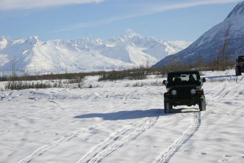 2003 Jeep TJ - Two Jeeps navigate a snow-covered path with a mountain range under a clear blue sky.