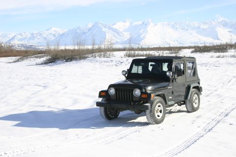 2003 Jeep TJ - A black Jeep TJ is parked in a snowy landscape with mountains in the background.