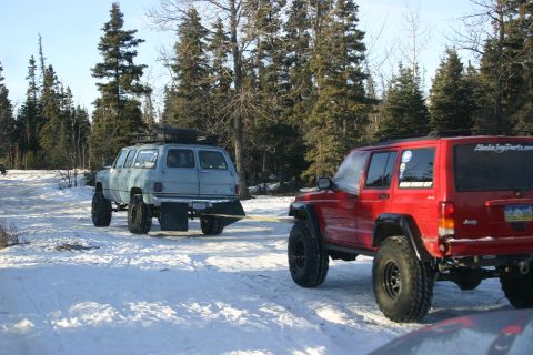 2003 Jeep TJ - A red Jeep Cherokee tows a light blue SUV through a snowy, wooded area.