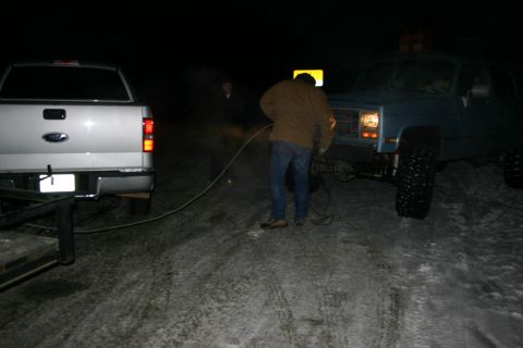 2003 Jeep TJ - Two trucks are being connected by a tow rope on a snowy road at night.