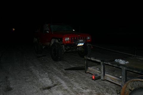 2003 Jeep TJ - A red Jeep Cherokee XJ is parked on a snowy road at night, attached to a trailer.