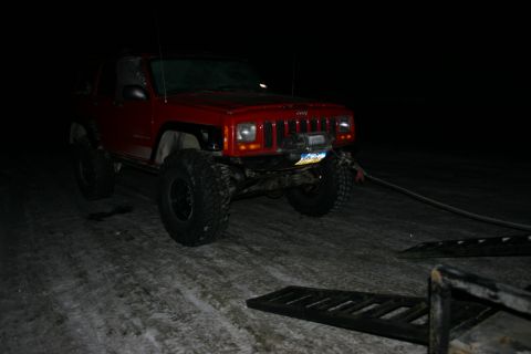 2003 Jeep TJ - A red Jeep Cherokee XJ is parked on a snowy road at night, attached to a winch.